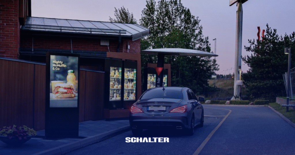 Carro estacionando em um Drive thru do McDonalds com um ODMB na entrada.